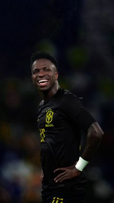 a man with his hands on his hips wearing a black shirt and yellow writing on the chest