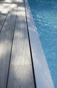 an empty swimming pool with water running down the side and wood flooring around it