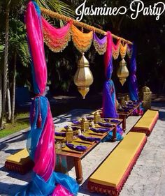 a long table with purple and blue cloths on it is set up for a party