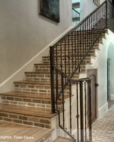 the stairs are made of wood and wrought iron, along with brick tiles on the floor