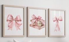 three framed pictures with pink bows and books in them on the wall above a bed