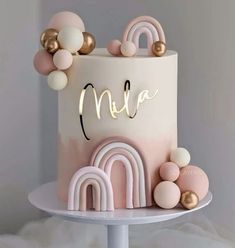 a pink and gold birthday cake with balloons on top that spell out the name mia