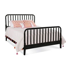 a black metal bed frame with pink and white pillows