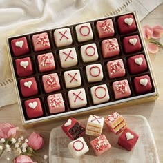 a box of valentine's day chocolates next to some pink flowers and tulips