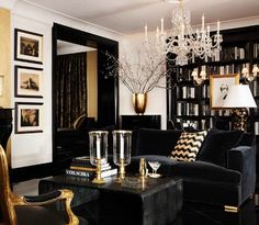 a living room filled with black furniture and a chandelier hanging from the ceiling