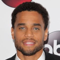 a close up of a person wearing a suit and tie with an afro hairstyle