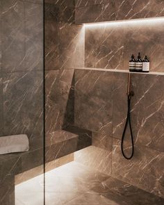 a bathroom with marble walls and tile flooring, including a glass shower door that has lights on the side