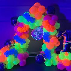 an arch made out of balloons and streamers with a happy birthday sign in the center