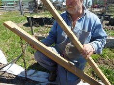 a man sitting on the ground holding two wooden planks