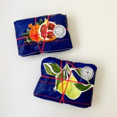 two pieces of blue wrapping paper tied to each other with fruit and leaves on them