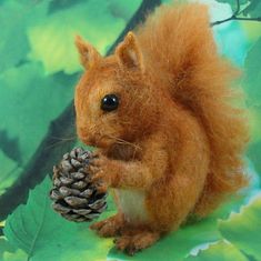 a needle - felt squirrel holding a pine cone