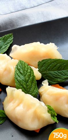 dumplings with mint leaves on a black plate