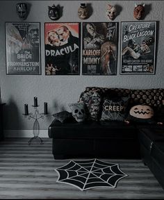 a living room filled with black furniture and posters on the wall above it's couch