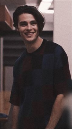 a smiling young man wearing a black and red shirt