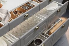 an open drawer with dishes and utensils in it on top of a table