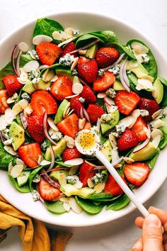 a salad with strawberries, avocado and dressing