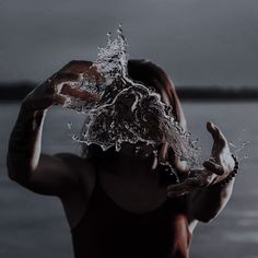 a person holding their head in the air with water splashing out of it's hands