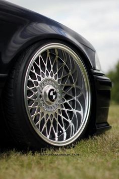 a black car with chrome rims parked in the grass