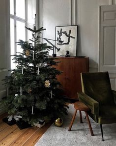 a living room with a christmas tree in the corner and a chair next to it