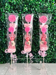 three candy lollipops in clear plastic bags on top of a table next to a green wall