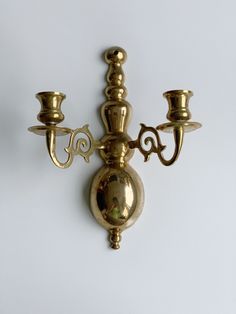 a wall mounted brass candle holder with two candles