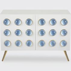 a white cabinet with blue circles on the front and gold legs, against a gray background