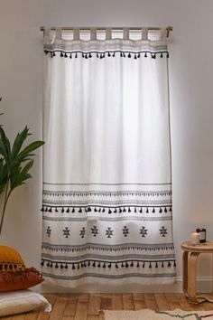 a white curtain with black and white designs hanging from it's side in a living room