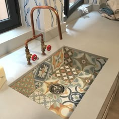 a sink in a bathroom with colorful tiles on the floor and walls behind it, next to a window