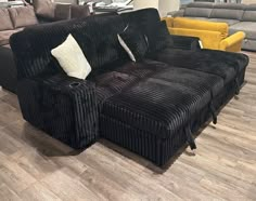 a large black couch sitting on top of a wooden floor next to two yellow chairs