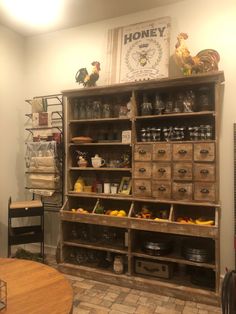 an old wooden shelf filled with lots of food and other items in a room next to a table