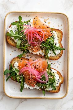 two pieces of bread topped with salmon and greens