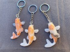 two fish shaped key chains are shown on a gray surface, one is orange and the other is white