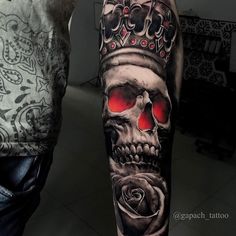 a man's arm with a skull wearing a crown and roses tattoo on it