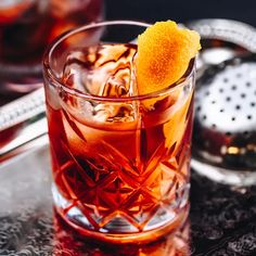 a close up of a drink in a glass with an orange peel on the rim