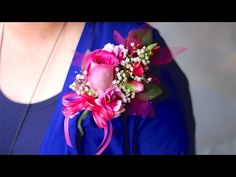 a woman wearing a blue top holding a pink rose and baby's breath