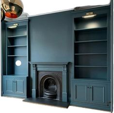 an empty living room with dark blue painted walls and built - in bookcases