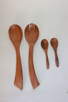 four wooden spoons and two forks on a white surface