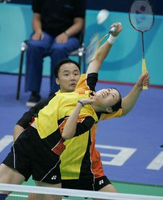 two people playing tennis on a court with one holding the racket in the air