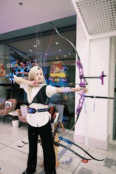 a woman in white shirt holding a bow and arrow