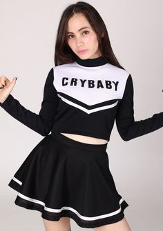 a girl in a black and white outfit posing for the camera with her hands up