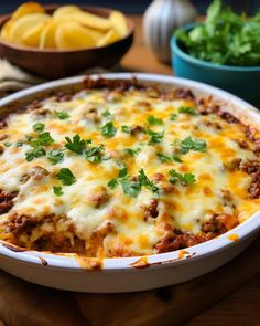 a casserole dish with cheese, meat and vegetables in the background on a cutting board