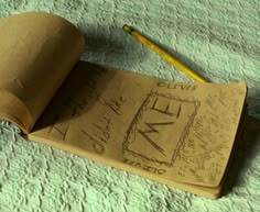 an open book with writing on it next to a pencil and paper towel covered tablecloth