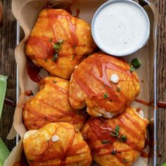 some food that is sitting in a box on a wooden table with sauce and ketchup