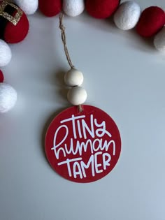 a red and white ornament with the words tiny human tamer on it