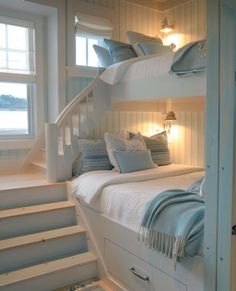 a bedroom with bunk beds and stairs leading to the upper floor, along with two windows