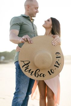 a man and woman standing next to each other with a hat on their shoulders that says,