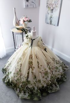 a dress on display in a room with flowers and paintings behind it, including a mannequin's head