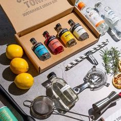 an assortment of cocktails and gin in a box on top of a table with lemons