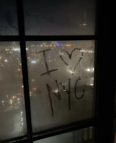 i love nyc written in frosted glass on a window at night with city lights