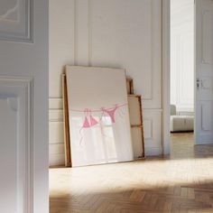 an empty room with white walls and wooden flooring is decorated with pink clothes hanging on a line